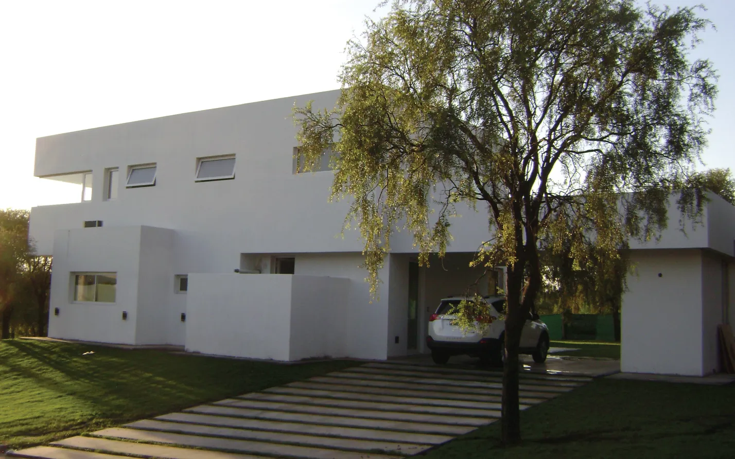 Casa blanca de dos plantas con jardín
